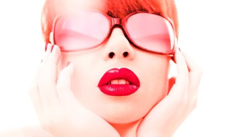 Glamour photo of red haired young woman in red lipstick and red sunglasses