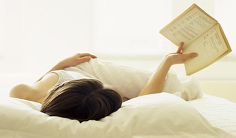 woman reading in bed holding book